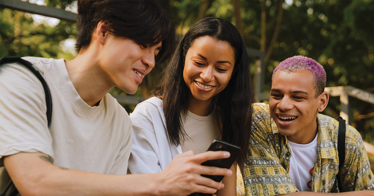 Teens smiling looking at a phone.